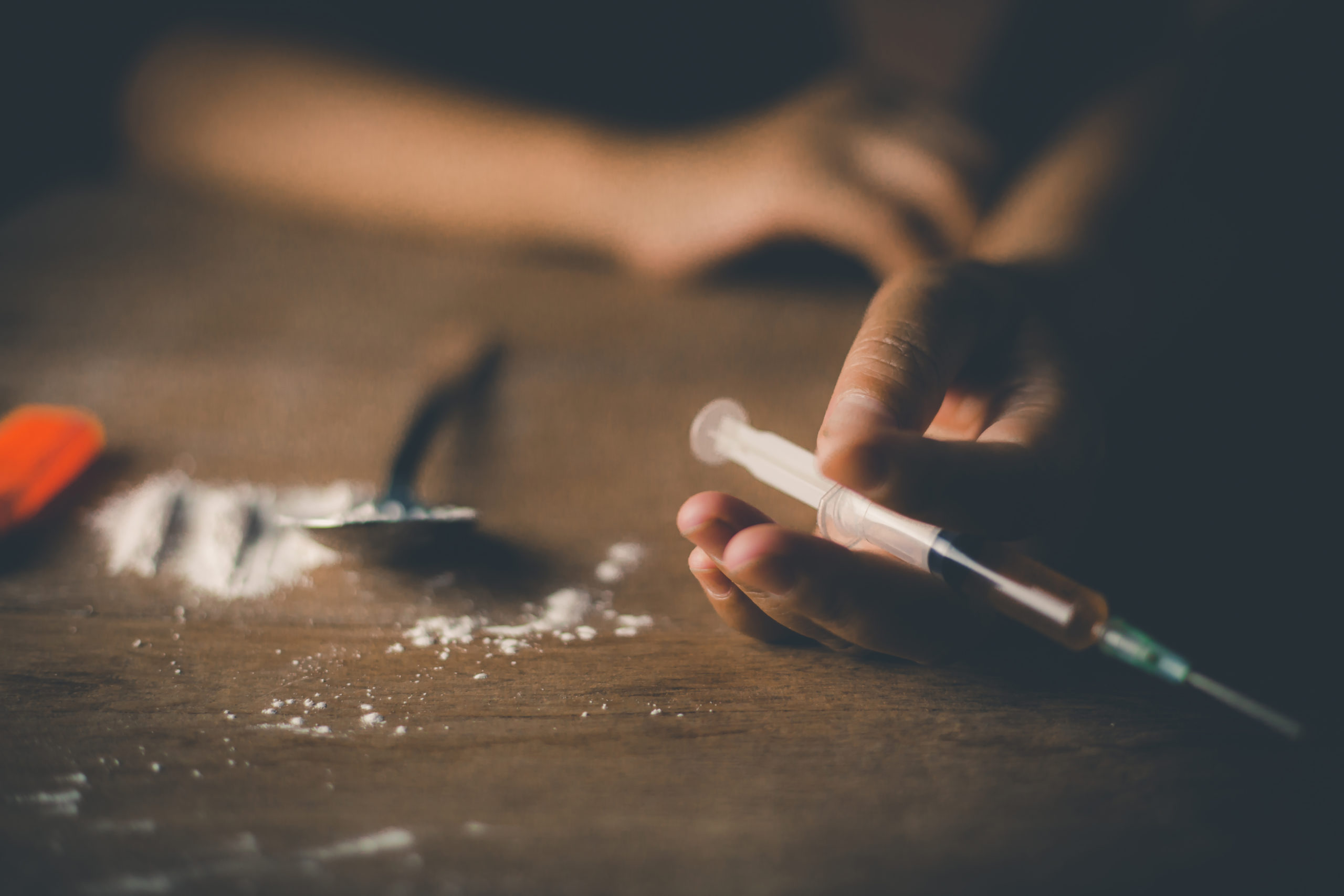 Hands on table holding needle filled with opioids
